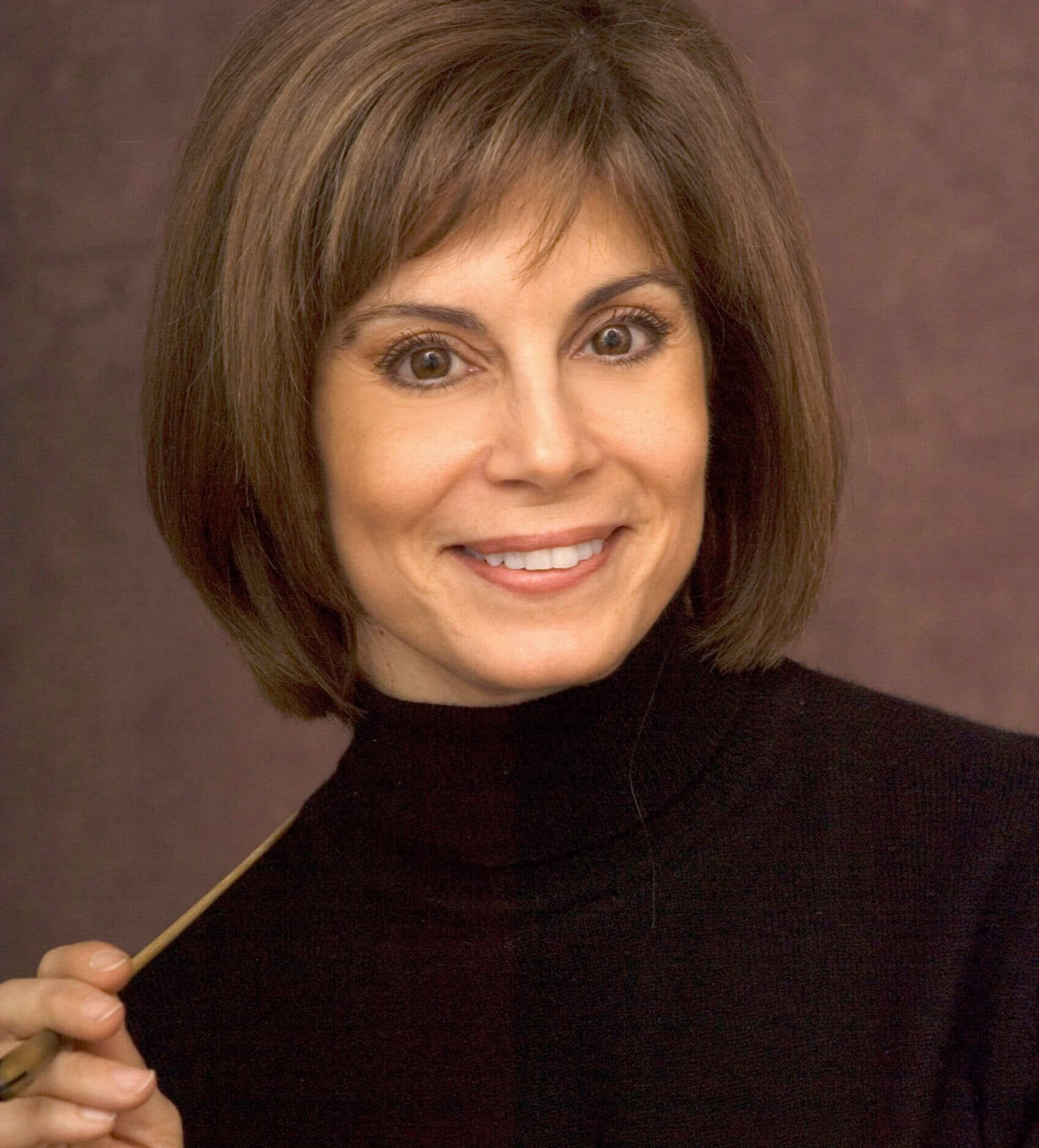 JoAnn Falletta holding a conductor's baton and smiling at camera