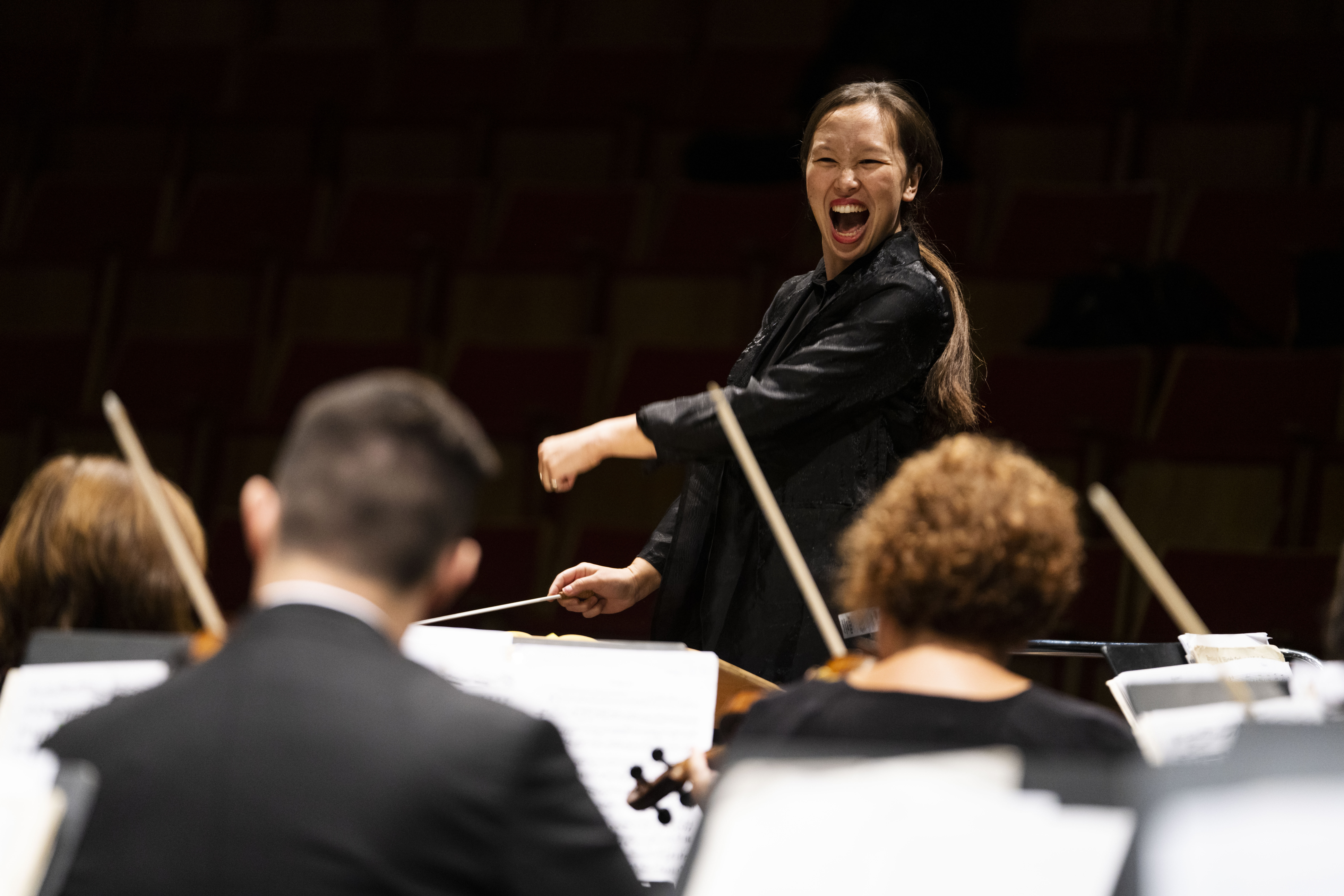 Conductor Naomi Woo emphatically leading an orchestra