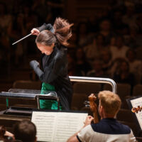 Conducting Fellow Naomi Woo stands on the conducting podium.