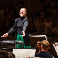 Conducting Fellow Naomi Woo stands on the conducting podium.