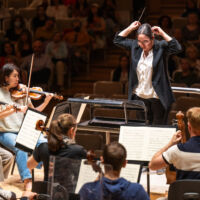 Conducting Fellow Jennifer Tung stands on the conducting podium.