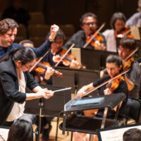 Conducting Fellow Jennifer Tung stands on the conducting podium.
