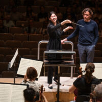 Conducting Fellow Monica Chen stands on the conducting podium.