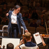 Conducting Fellow Kelly Lin stands on the conducting podium.
