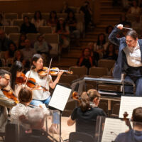 Conducting Fellow Kelly Lin stands on the conducting podium.